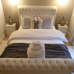 Aaron sleigh bed in white faux leather, offering a chic and timeless design for any bedroom.